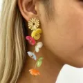 Detailed close-up view of the colorful resin flower long dangle earrings worn on ear. Elegant design. - Multicolor