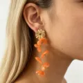 Long floral resin drop earrings detail view, golden metal and orange petals, elegant style. - Orange
