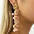Close-up of long dangling pink resin flower earrings with gold metal stud for women detail. - Pink
