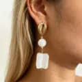 Close-up detail shot of French retro resin square pendant drop earrings worn on ear. - White