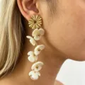 Long floral drop earrings featuring white resin petals and gold-toned metal design details. - Milky White