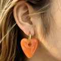 Stainless steel hoop earrings with detachable orange marble resin heart pendant detail view - Orange