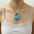Closeup view of the blue acrylic oval pendant on a gold stainless steel chain necklace style. - Blue