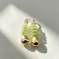 Close-up view of vintage geometric flower drop earrings with pale green discs and gold charm. - 5#