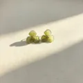 Close-up detail of green resin flower stud earrings featuring a chic gold tone bead center. - Green