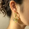 Close-up detail of metallic flower pendant hoop earrings with yellow bead accent fashion style. - Yellow