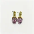 Gros plan détail des boucles d'oreilles fraise violette, design clou coquillage plaqué or. - Violet