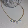 Detail shot of shell letter LOVE beaded necklace pendant close-up, simple clavicle jewelry. - LOVE