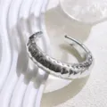 Close-up detail of the wide textured silver open cuff bracelet showing modern minimalist style. - Silver-Tone Narrow Polka Dot Bangles
