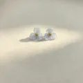 Close-up of sweet blue resin flower stud earrings with a gold bead center, elegant detail. - Light Blue