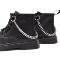 Close-up view of black combat boots with stylish silver chain accessory and lace-up details. - Silver Tone