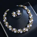 Close-up detail of luxury vintage gold pearl necklace and earrings set with rhinestone leaf accents. - White Pearl Necklace And Earrings