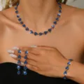 Dettaglio in primo piano di set collana, orecchini e bracciale con strass blu. - Completo 3 Pezzi Blu