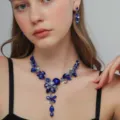 Dettaglio di una collana floreale in cristallo blu con orecchini coordinati per feste eleganti. - Stile Catena di Fiori a Y (80835408)