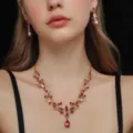 Dettaglio in primo piano della parure di gioielli con collana e orecchini di cristalli rossi. - Stile Cluster di Fiori a Cuore (80820703)