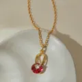 Gros plan d'un collier pendentif élégant en pierre rouge avec une chaîne plaquée or. - Style Rouge Blanc Étincelant (KN0709)