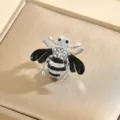 Primo piano dettagliato di una spilla ad ape con strass scintillanti e dettagli in smalto nero. - Stile Ape Argentata Strass Ala Nera (9296-2)