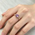 Nahaufnahme Detail des goldenen Luxusrings mit lila Rundstein und funkelnden Zirkonia Steinen. - Violetter Strass Stil / Gold