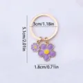 Purple enamel flower keychain accessory, gold ring pendant with dual floral charms design. - Purple Flower