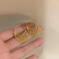 Nahaufnahme im Detail von koreanischen minimalistischen goldenen Creolen mit Lochmuster. - Gold
