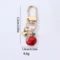 Gold tone metal keychain featuring a red apple pendant and heart charm for bags or cars. - Rhinestone Red Apple