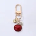 Gold-tone metal apple keychain with red enamel pendant, sparkling rhinestone leaf, and heart charm. - Medium Red Apple