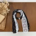 Detailed view of the elegant black and white lace splicing scarf with a pearl buckle accessory. - Coffee