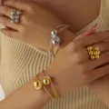 Primo piano di eleganti anelli di perline metalliche e bracciali aperti indossati, design moderno. - Set da 4 Pezzi (0052)