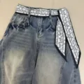 Close-up detail of vintage wash denim jeans featuring black and white paisley print ribbon. - Edged Paisley / 140x7cm / Black