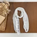 Detail shot of a women's polka dot lace patchwork scarf with elegant pearl buckle accessory. - Off White