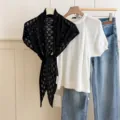 Detailed view of the black hollow-out knitted triangular scarf styled with casual daily wear. - Black