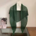 Detailed view of the dark green hollow knit triangular scarf and shawl for summer styling. - Green