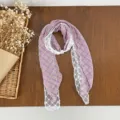 Detailed shot of a purple plaid scarf featuring delicate white lace trim and chic pearl decoration. - Purple