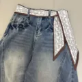 Detail shot of retro washed blue jeans featuring brown paisley print ribbon belt decoration. - Edged Paisley / 140x7cm / Coffee