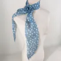 Détail en gros plan d'un foulard en mousseline à pois bleus avec une rose 3D amovible. - Rose à pois bleu brume