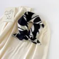 Close-up detail view of a chic black and white abstract print square scarf styled on knitwear. - 68x68cm / Abstract Art - Black