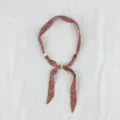 Detail view of the vintage floral silk scarf necklace with wooden and white beads accessory. - Broken Floral Orange Red