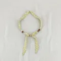 Close-up detail of green floral fabric scarf necklace with delicate wooden beads decoration. - Plain Small Floral Yellow