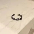 Vista detallada de un anillo abierto negro con diseño de espinas y cristales morados. - Estilo de Vid Estéreo (A1)