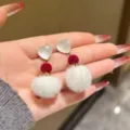 Primer plano detallado de los pendientes de corazón con pompón de felpa blanca, estilo otoño. - Pendientes de botón de pompón de corazón