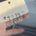 Primer plano de un juego de 6 pendientes plateados con dijes de estrellas, cadenas y zircones. - Juego de 6