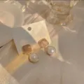 Primer plano detallado de pendientes geométricos color café con perlas, estilo retro. - Pendientes bicolor café