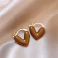 Primer plano detallado de pendientes de aro con corazón marrón, estilo francés retro elegante. - Pendientes de aro de corazón café con leche