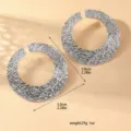 Primo piano dettagliato di grandi orecchini a cerchio aperti testurizzati argentati. - Stile Anello Cavo Grande Argentato (80118501)