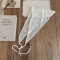 Gros plan détail du foulard triangle en tricot ajouré crème avec perles en bois. - Blanc