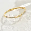 Foto di dettaglio del bracciale rigido geometrico dorato con pavé di strass scintillanti e intagli. - Stile Anello 3D (80511802)