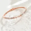 Primo piano dettagliato di un bracciale rigido geometrico in oro rosa con strass luminosi. - Stile Anello 3D (80511836)