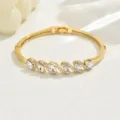 Elegante bracciale rigido geometrico in cristallo dorato con splendidi dettagli di strass. - Oro