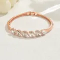 Elegante bracciale rigido in oro rosa con cristalli scintillanti e dettagli di strass. - Oro rosa