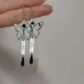 Vista detallada de pendientes retro de mariposa con colgantes de gota negros y texto. - Pendientes de mariposa de pintura en tinta